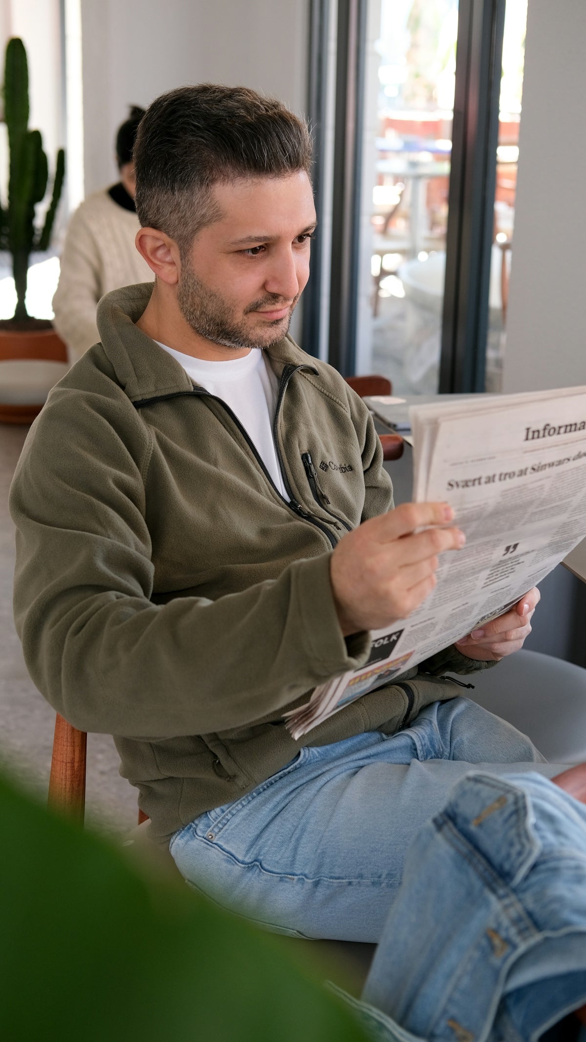 A man sitting in a chair reading a paper