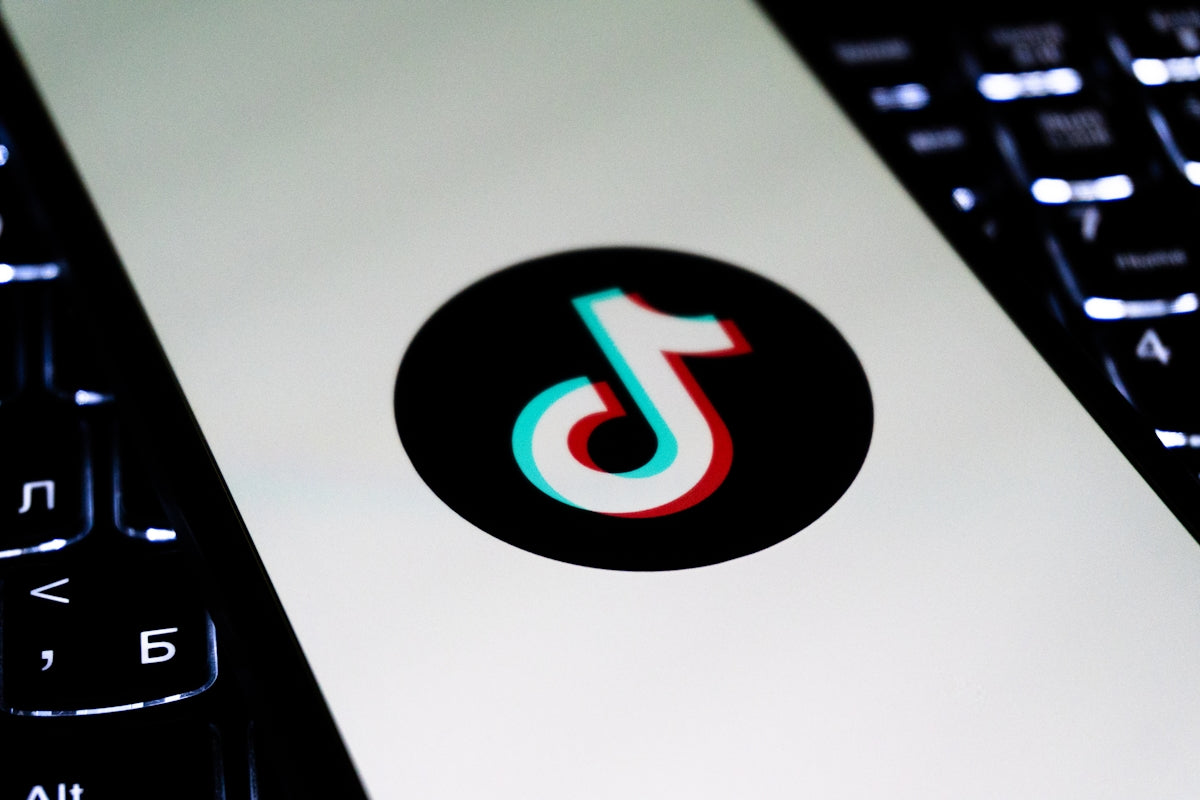 Tiktok logo on a white screen between keyboards