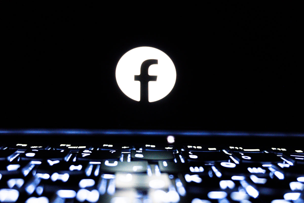 Facebook logo illuminated on a dark laptop screen.